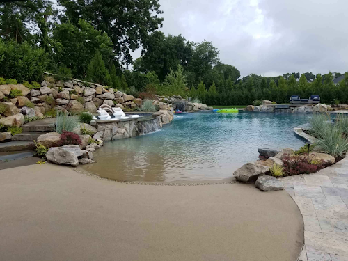 Sand sculpted pool with boulder retaining wall and walk-in beach entry