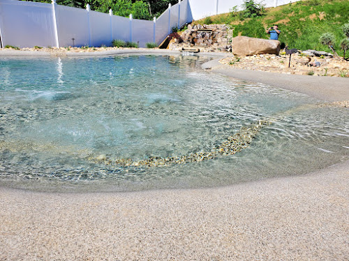 Water-level view of a sand sculpted beach entry with waterfall