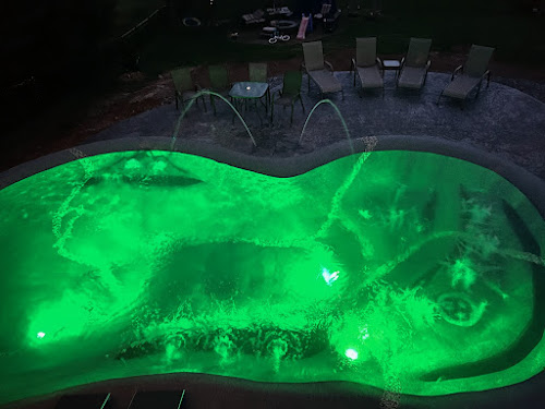 Sand sculpted pool lit green at night with laminar water features