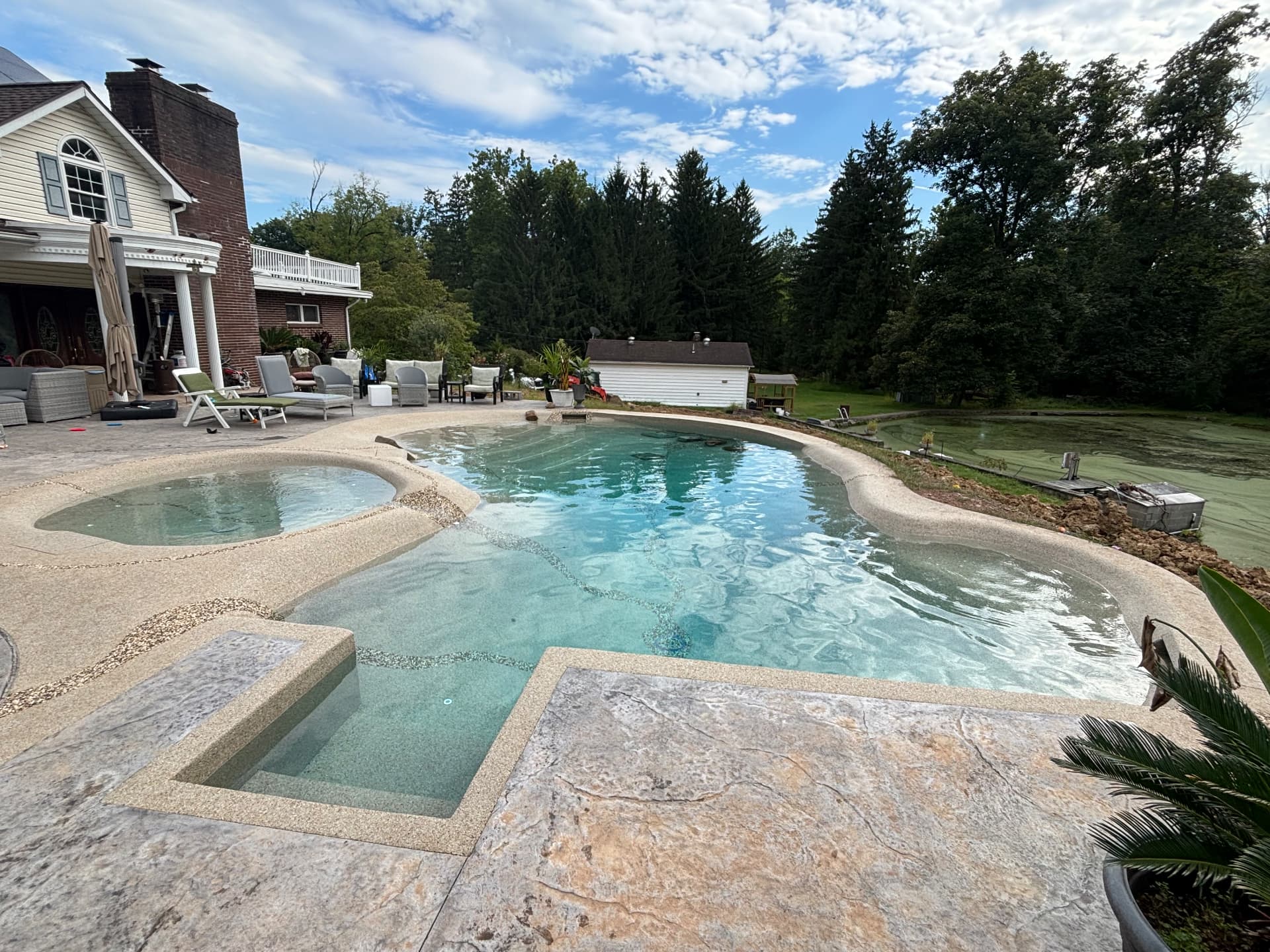 The finished Couch sand sculpted pool filled, with beach entries and boulder accents