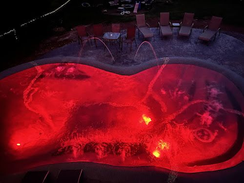 Sand sculpted pool lit red at night with laminar water features