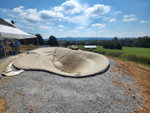 Sculpted pool basin during construction overlooking farmland