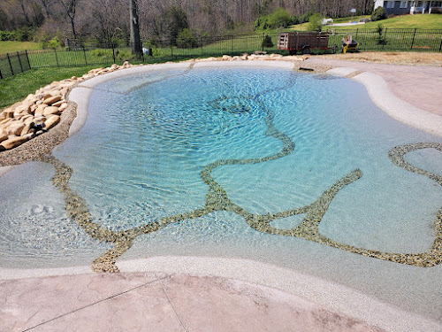 Wide sand sculpted pool with pebble channels and stone edging